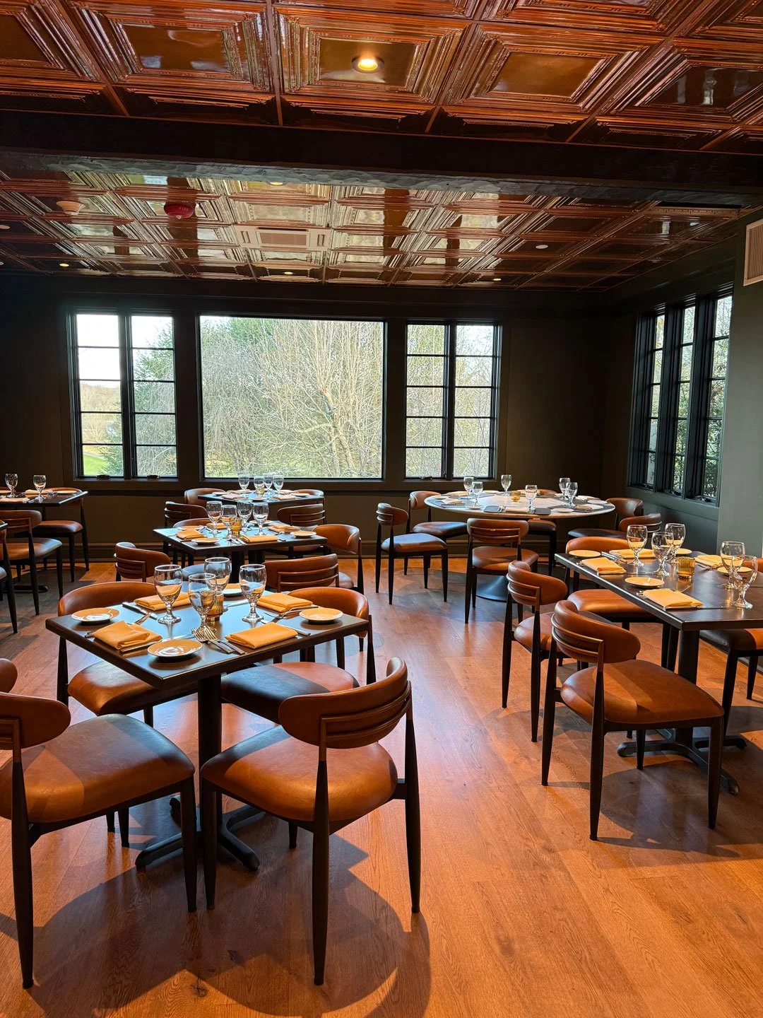 Previous founder of Kittle House Inn, John Crabtree, sitting in the dining room holding a glass of wine