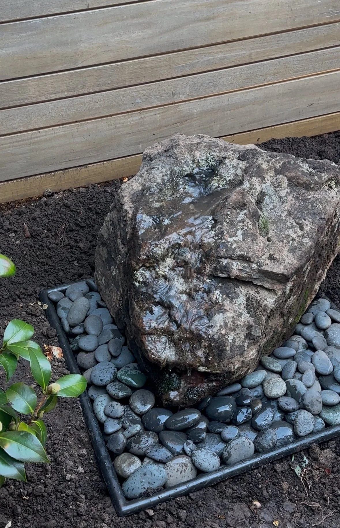 Fountain made from singular boulder on top of pebbles.