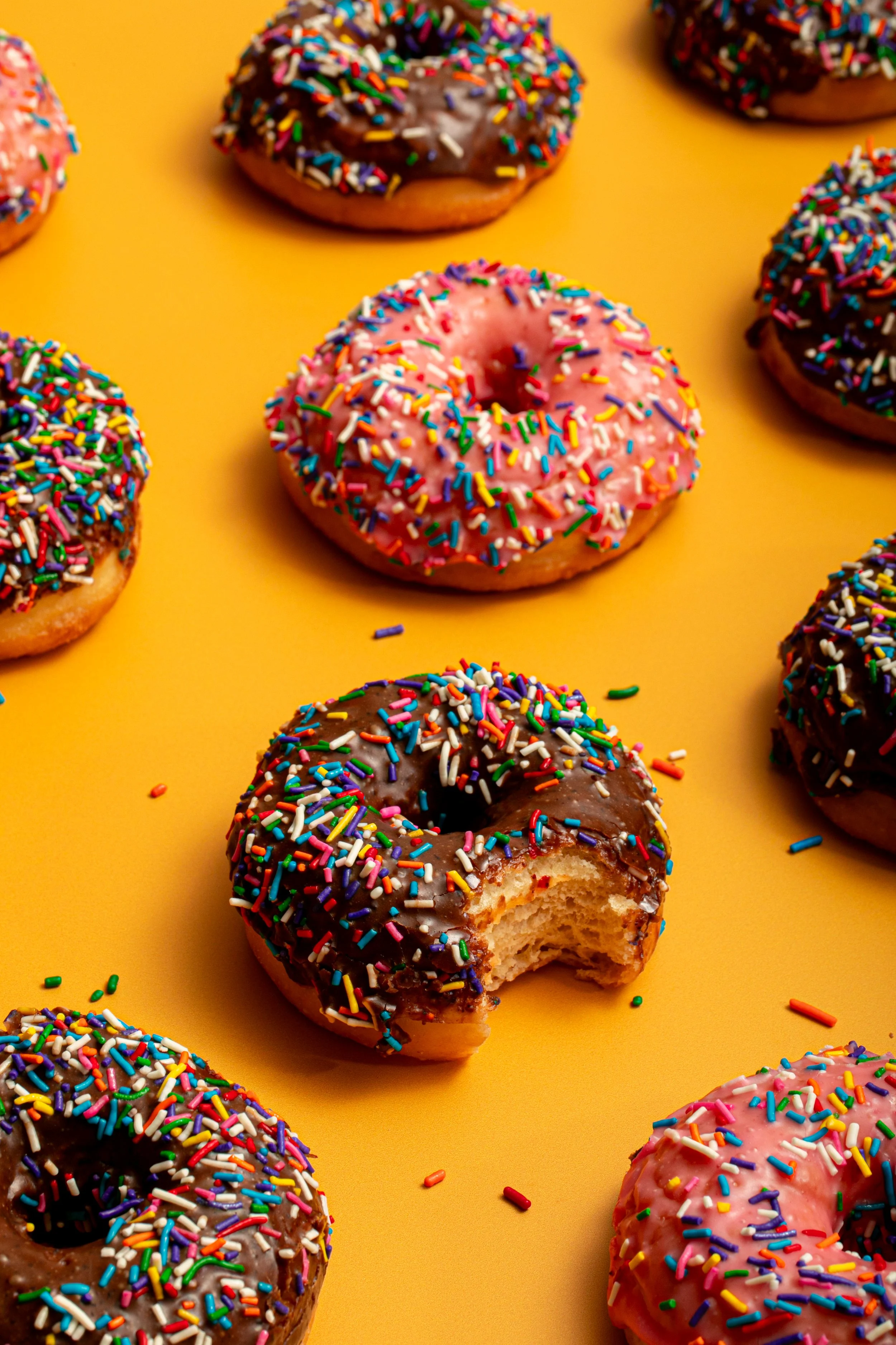 chocolate donut bite on bright yellow colorful background modern fun breakfast donut photography seattle baked goods photographer