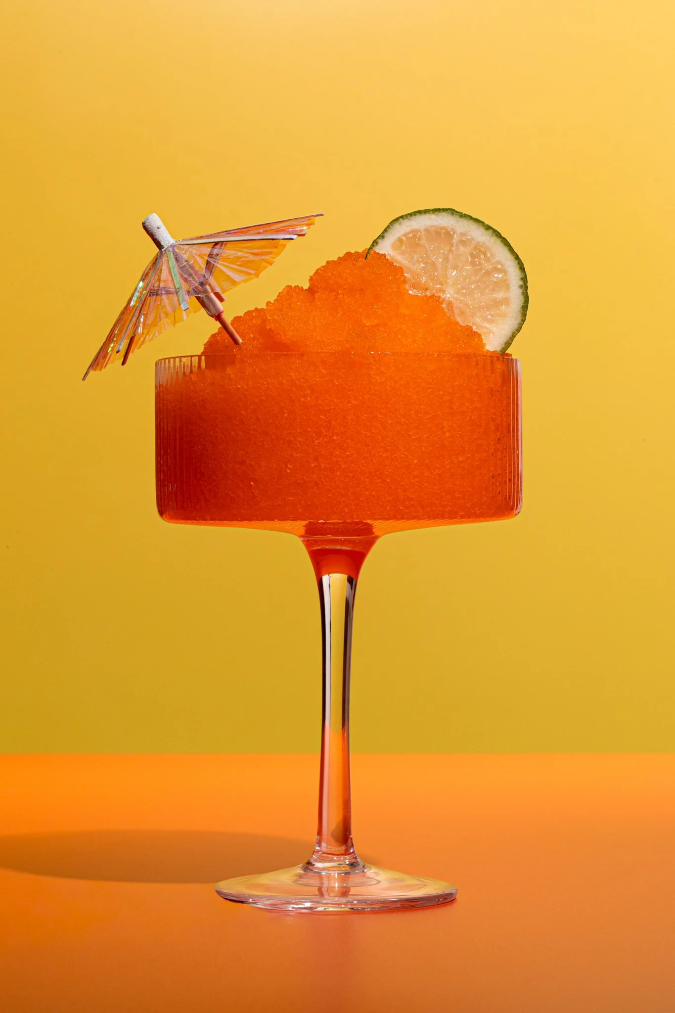 gorgeous orange slushy summer drink on a orange and yellow backdrop with moody summer lighting 