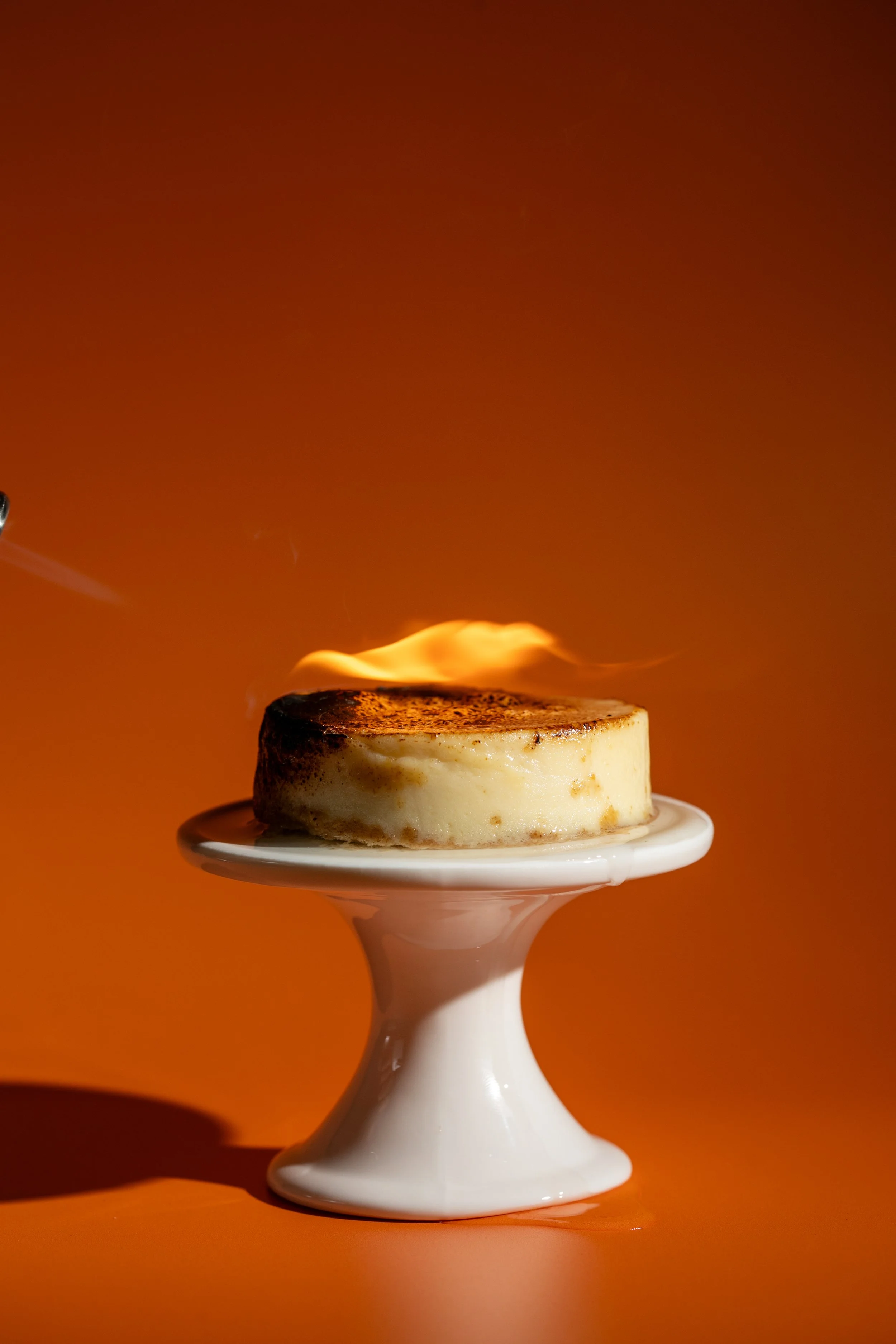 creme brulee cheesecake on fire bright orange colorful background seattle food photographer