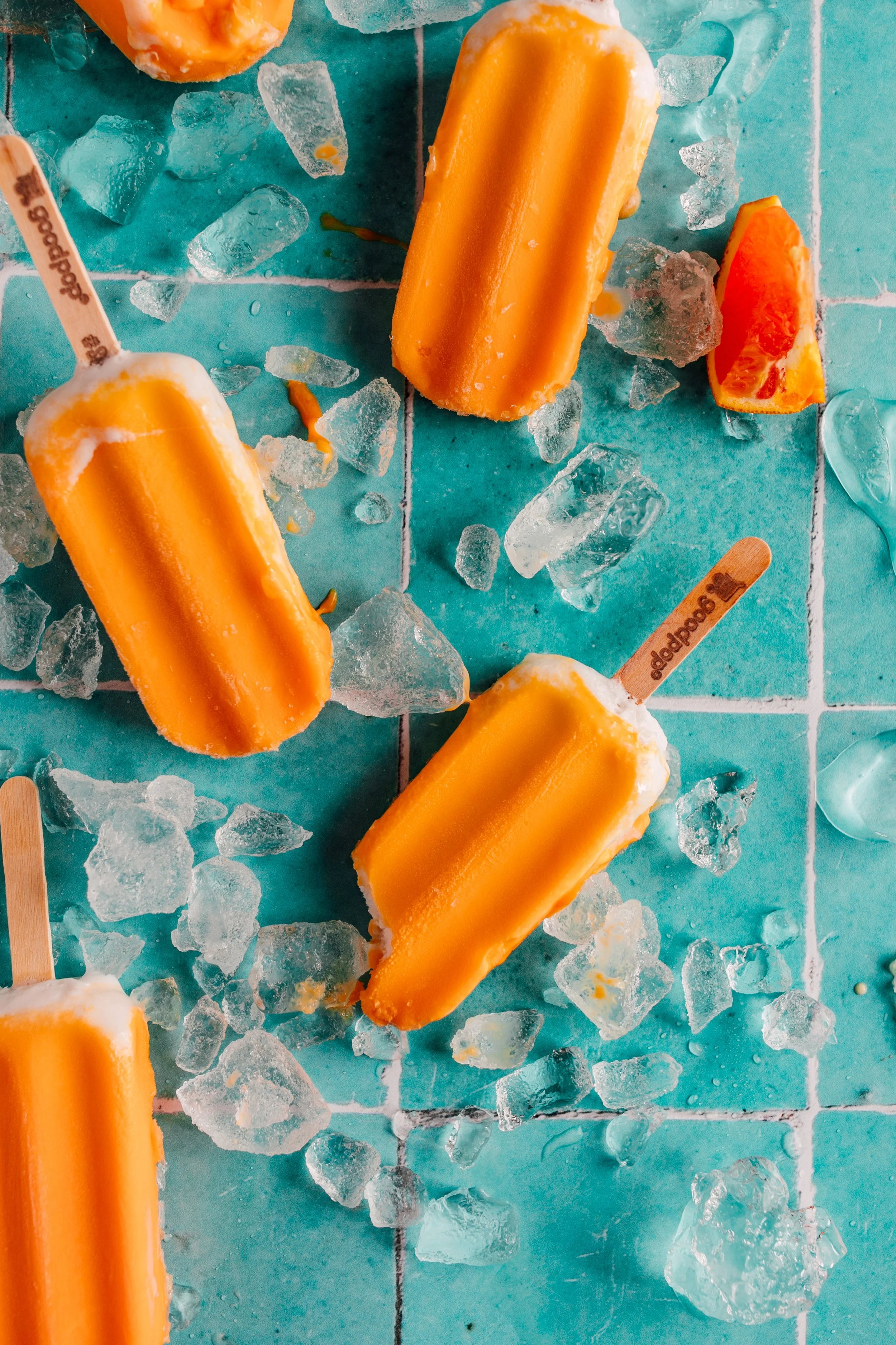 summer popsicle orange creamsicle goodpop thrown on tabletop with fresh ice summer dessert photographer seattle  