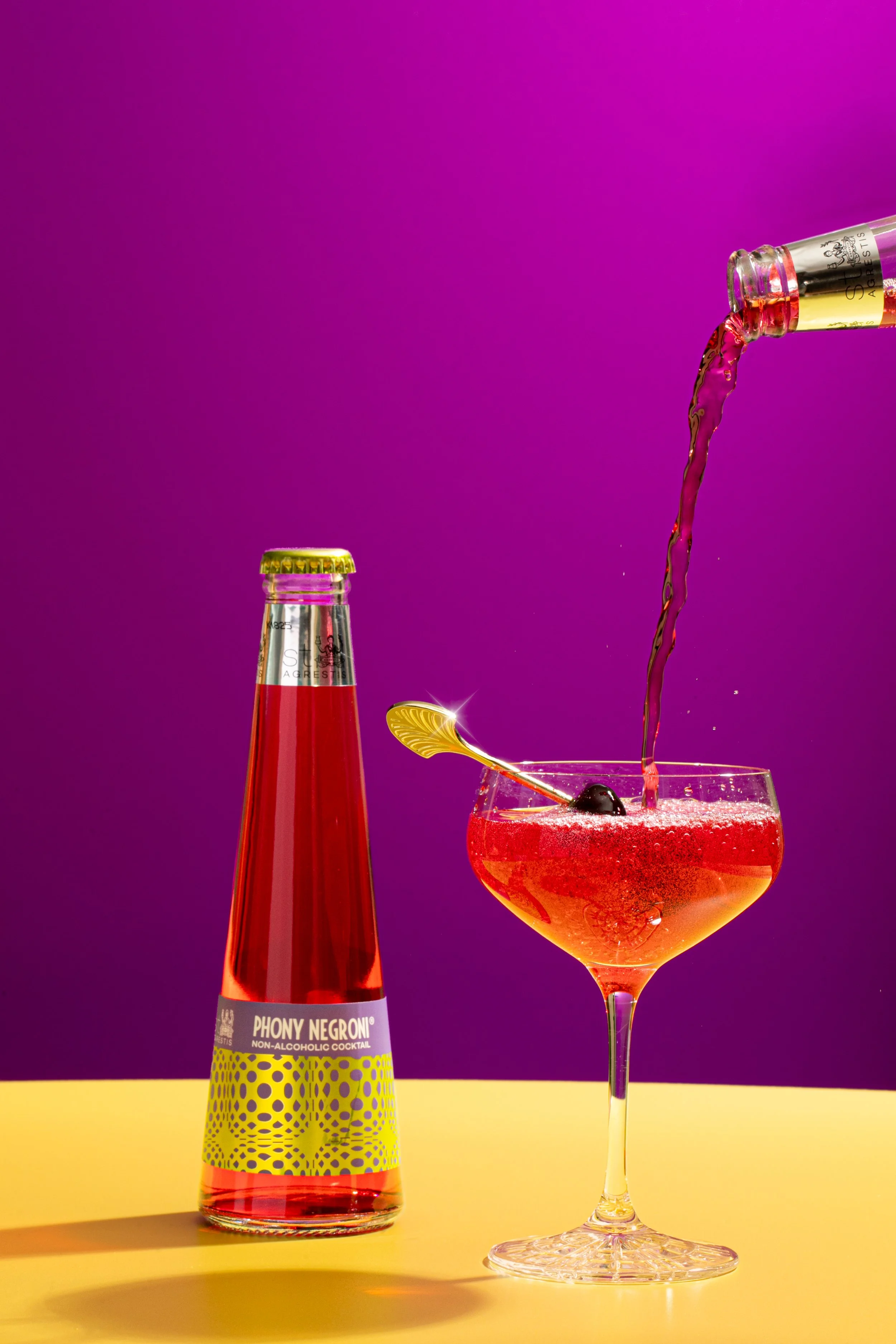 pouring a non-alcoholic negroni in a cute cocktail glass on bright pop art colors seattle food photographer
