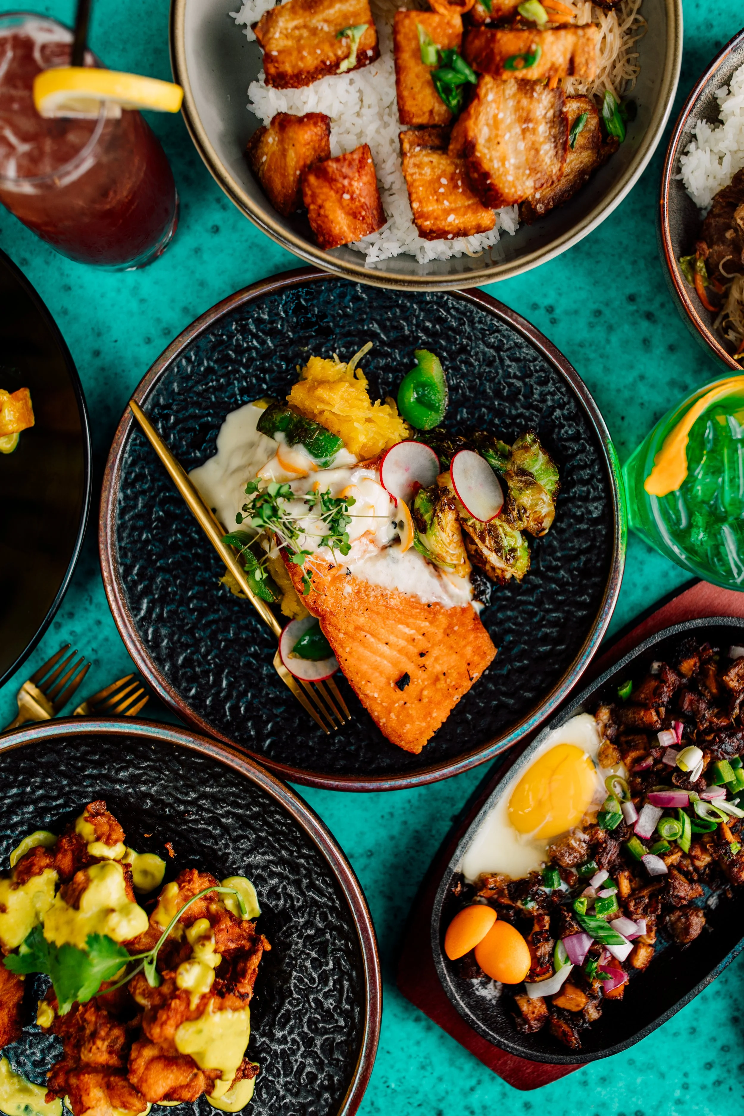 filipino style salmon plated on bright blue background on full table of food seattle restaurant photographer