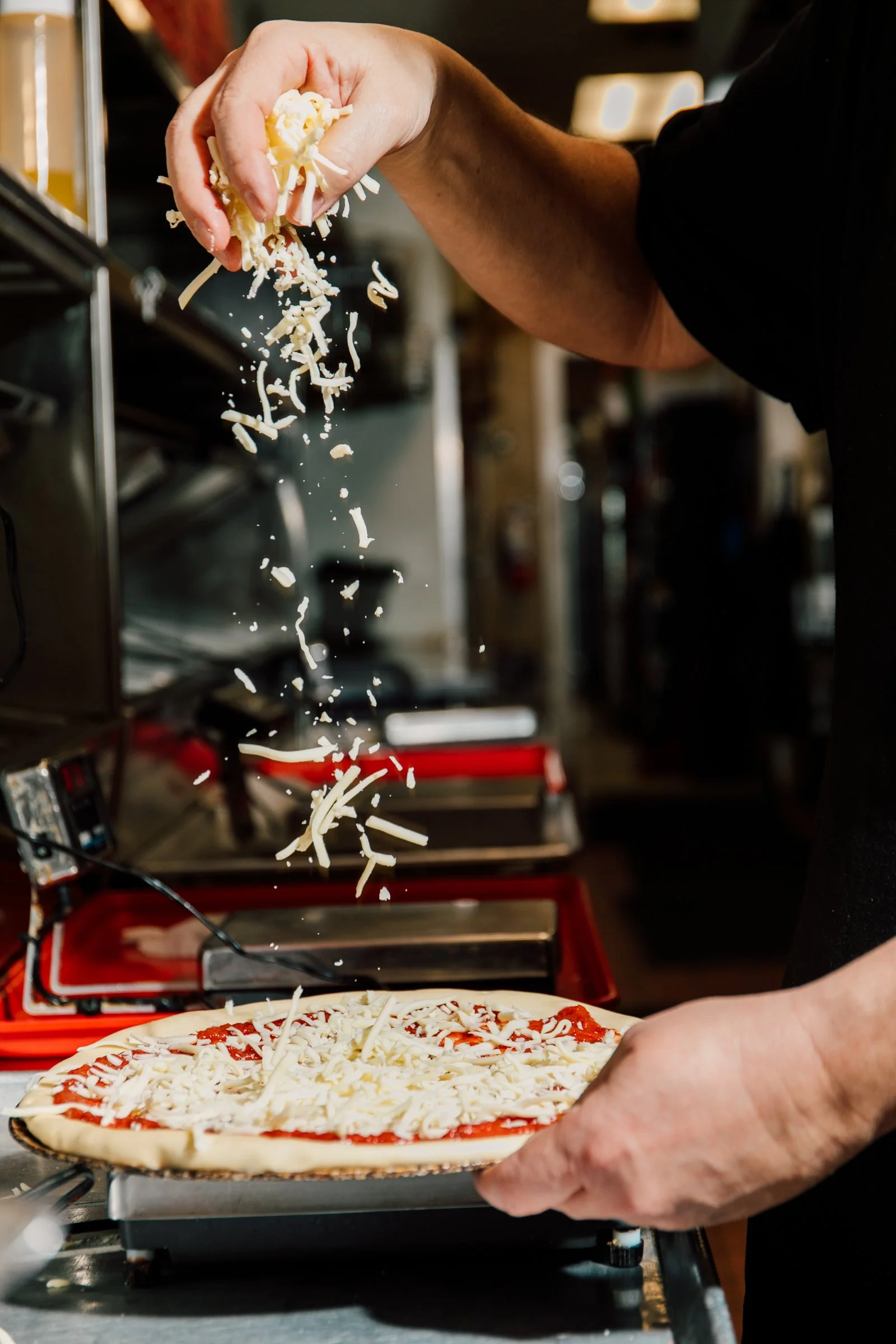 sprinkling fresh mozzarella cheese on a pizza seattle restaurant