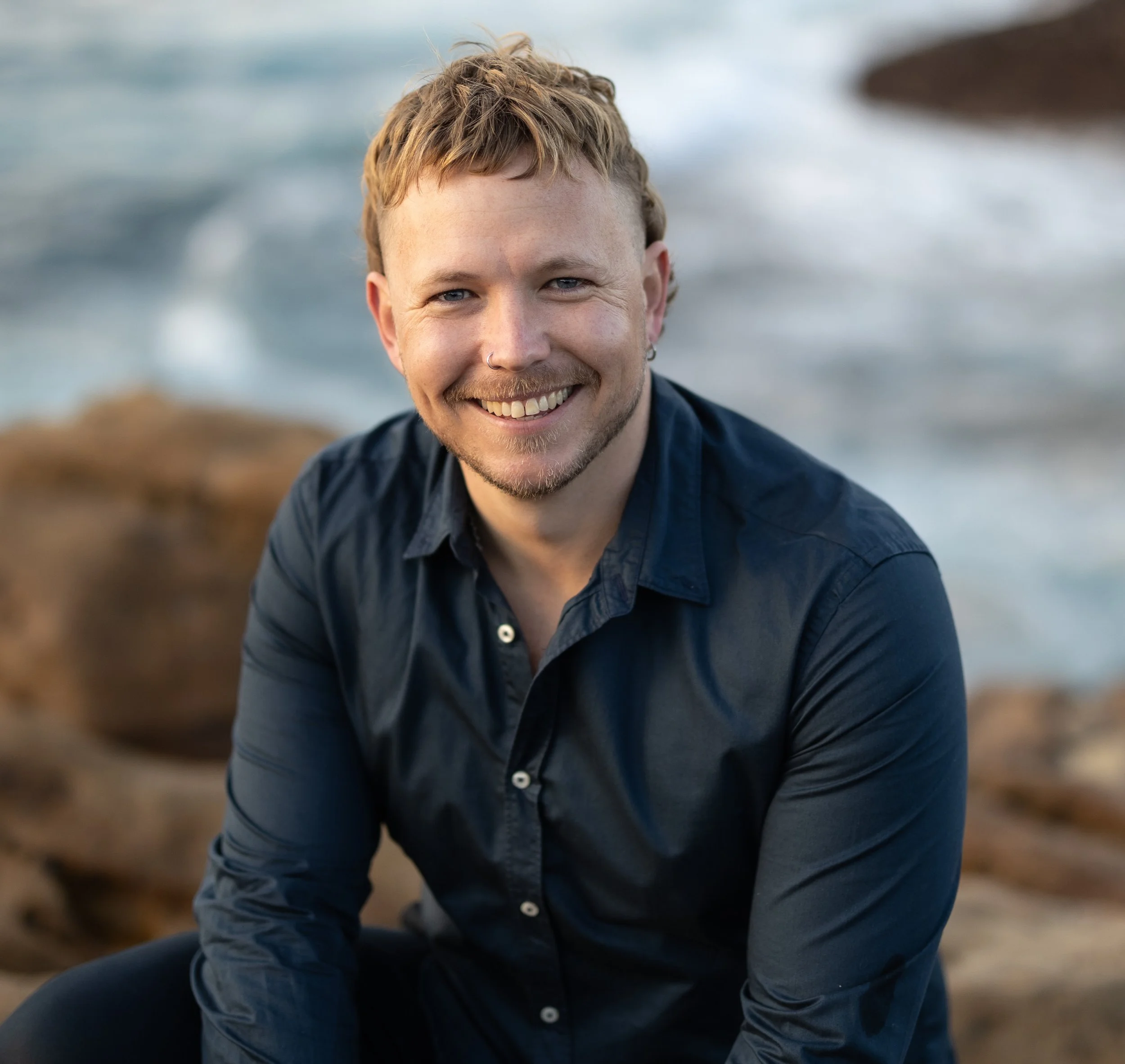 William Wolfenden, founder of LifeFlow Occupational Therapy, seated outdoors by the Sydney coastline