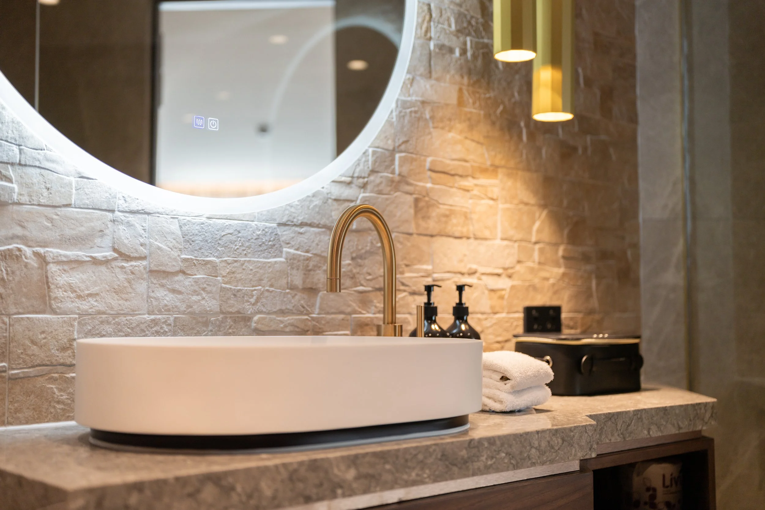 Freestanding bathtub with stone finishes and ambient lighting.