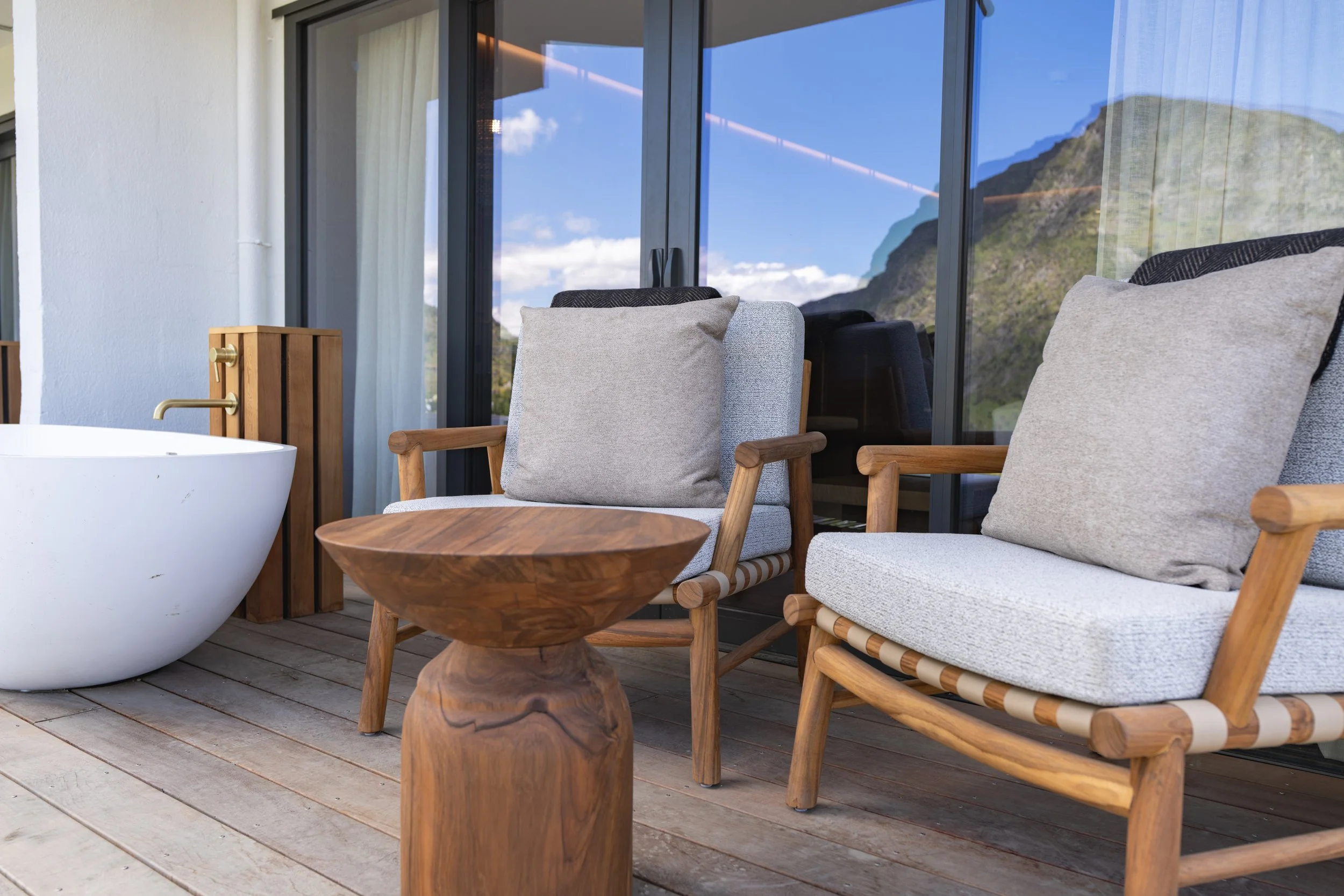 Outdoor seating area with cushioned chairs overlooking alpine landscape.
