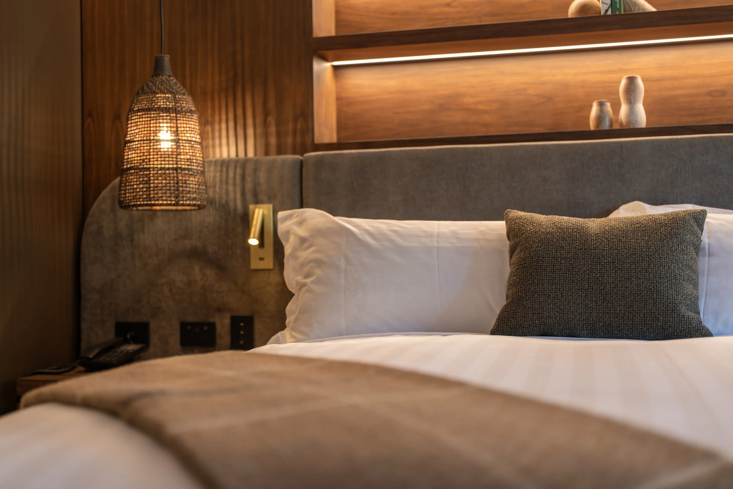 Plush bed with layered cushions and textured headboard in modern alpine room