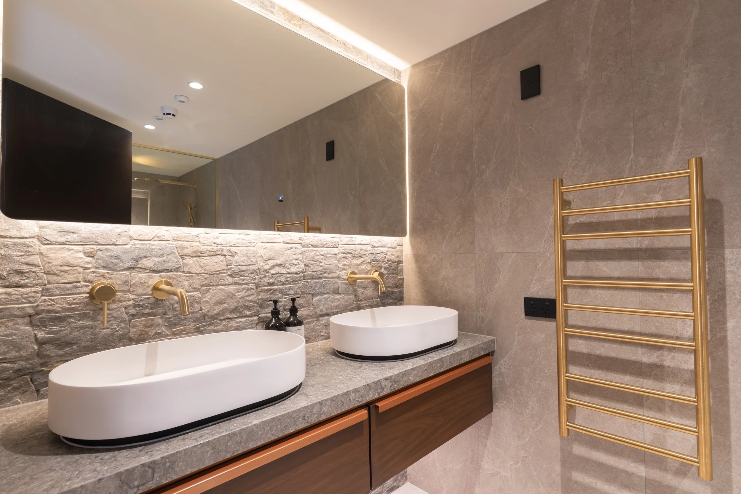 Modern ensuite bathroom with walk-in shower, stone finishes and backlit mirror at Coronet Ridge Resort.