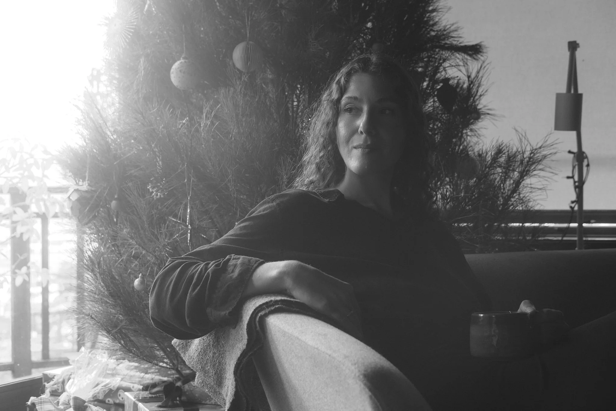 woman with curly hair in front of christmas tree