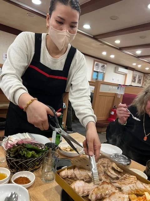 A woman serving food at a Korean restaurant.