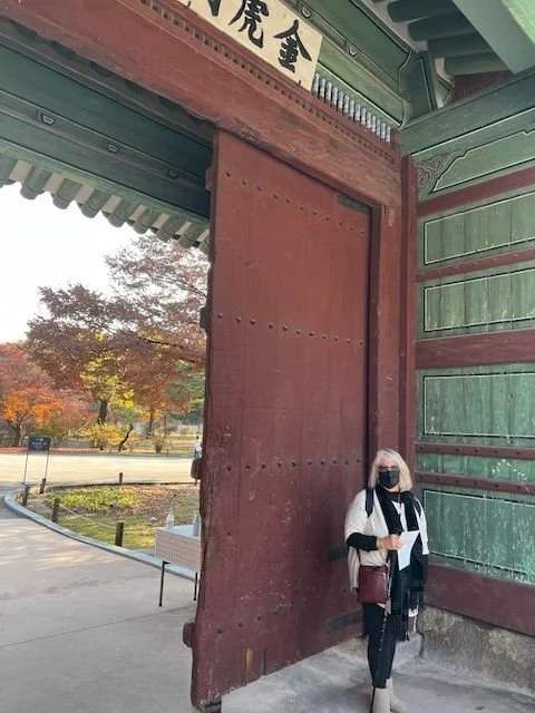 A woman standing in front of a palace door in South Korea