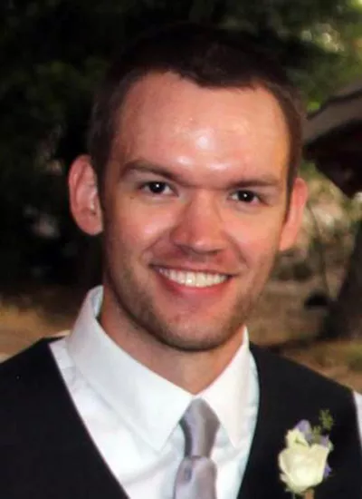 Andrew Bower smiling while wearing a tie and vest with a boutonniere.