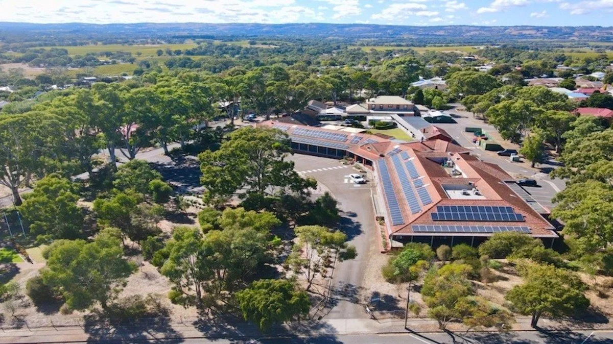 Aerial view of McLaren Vale hospital a building with solar panels, surrounded by trees and a rural landscape.