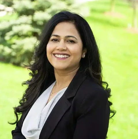 Two minimalist speckled ceramic vases, one with dried flowers, placed on a light surface against a neutral background.