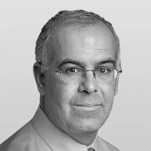 Black and white headshot of a middle-aged man with short hair, glasses, wearing a collared shirt, looking at the camera.