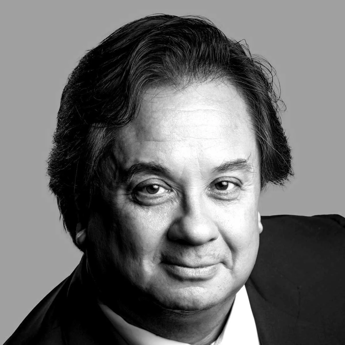 Black and white close-up portrait of a middle-aged man with dark hair, wearing a suit and smiling slightly.
