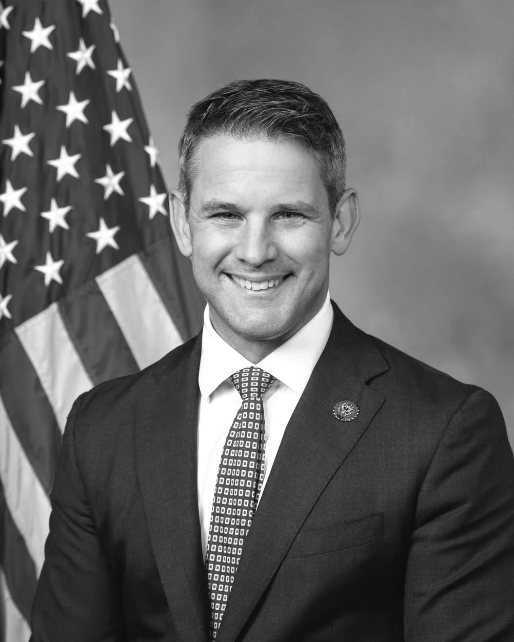 A black and white professional government headshot of Adam Kinzinger.