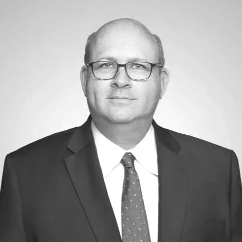 Black and white portrait of a man in a suit and tie wearing glasses.