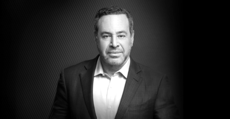 Black and white portrait of a man in a suit with a serious expression, background with subtle diagonal lines.