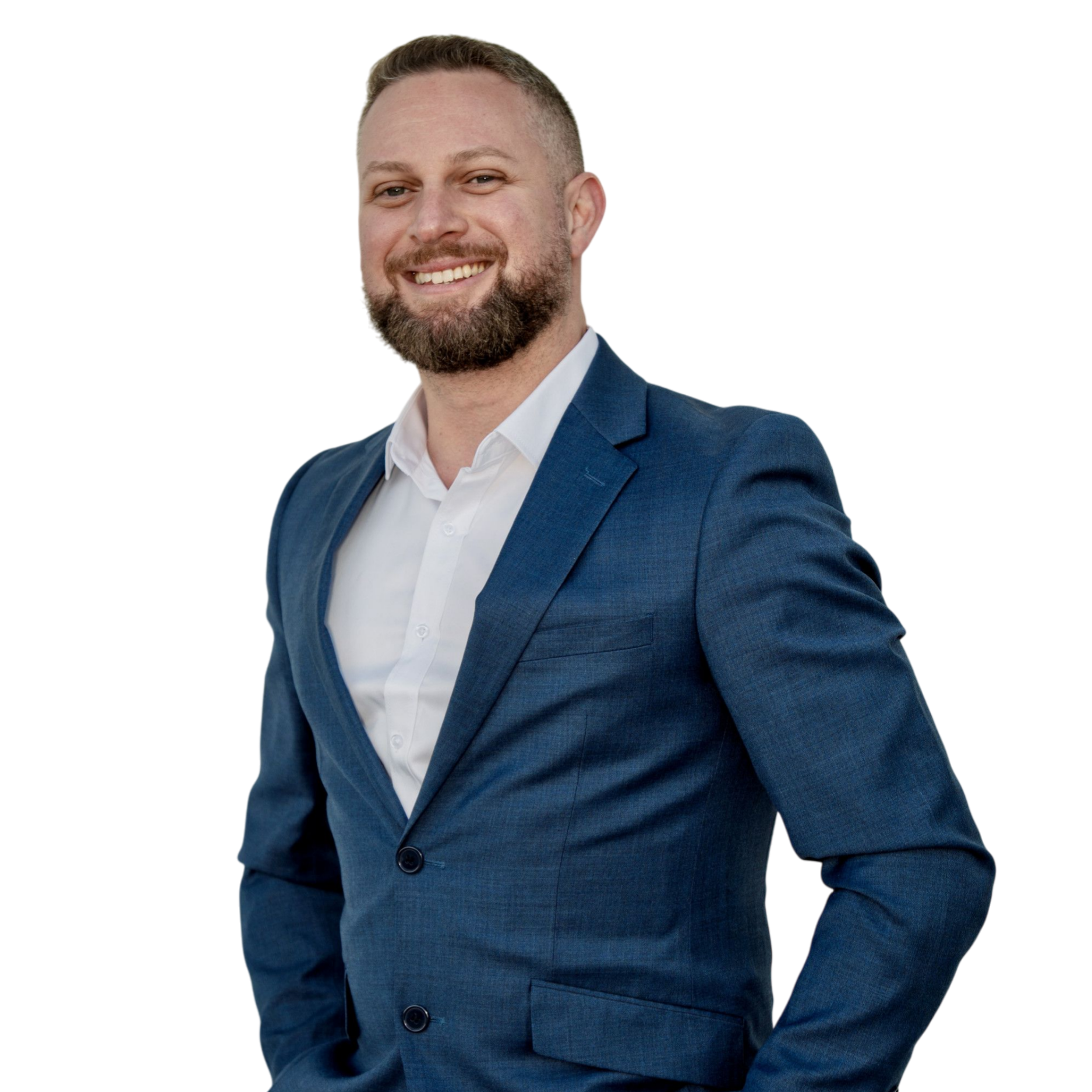 A smiling man in a blue suit with a white shirt, standing with one hand in his pocket against a black background.