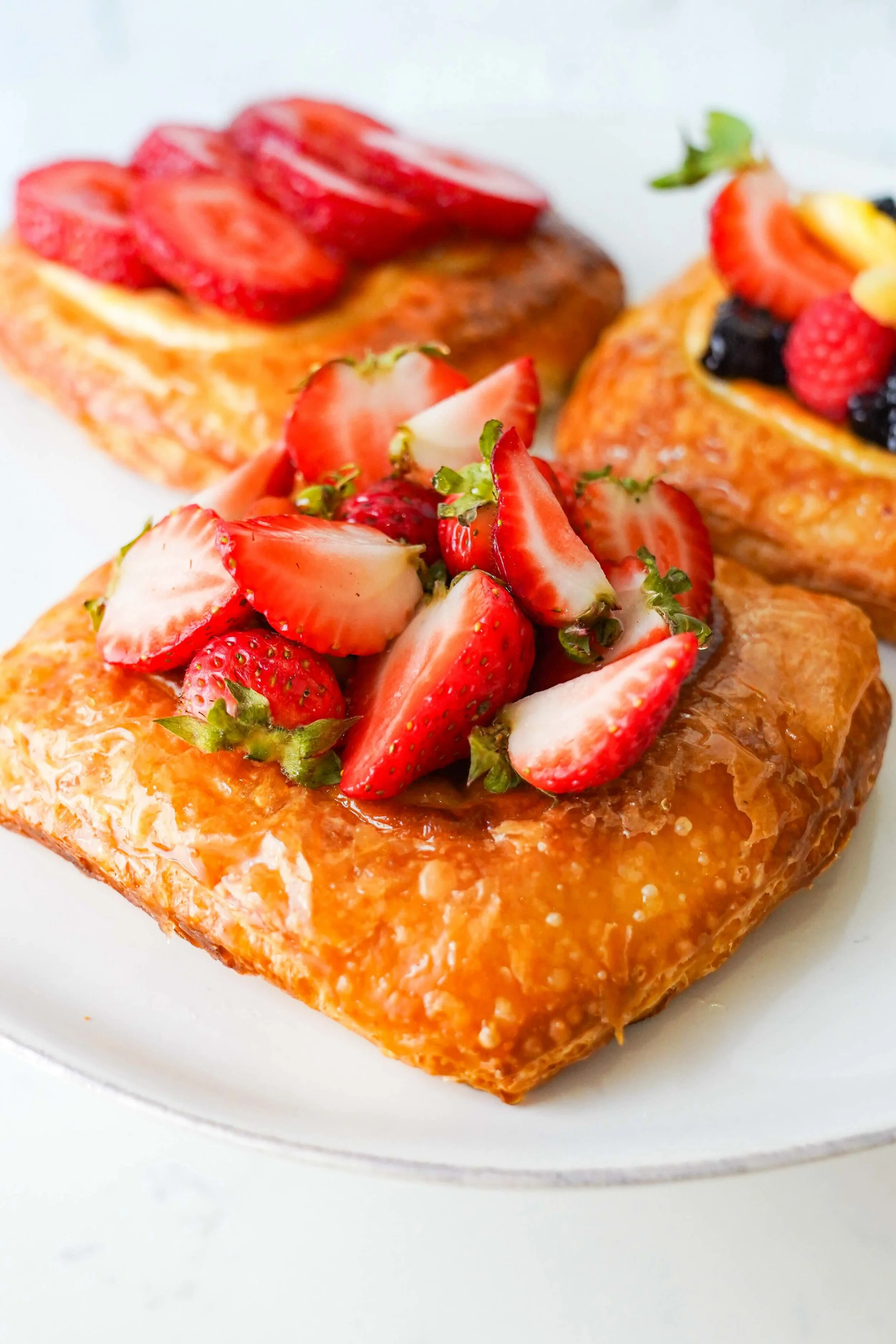 Assorted fruit pastries with strawberries and berries on a white plate.