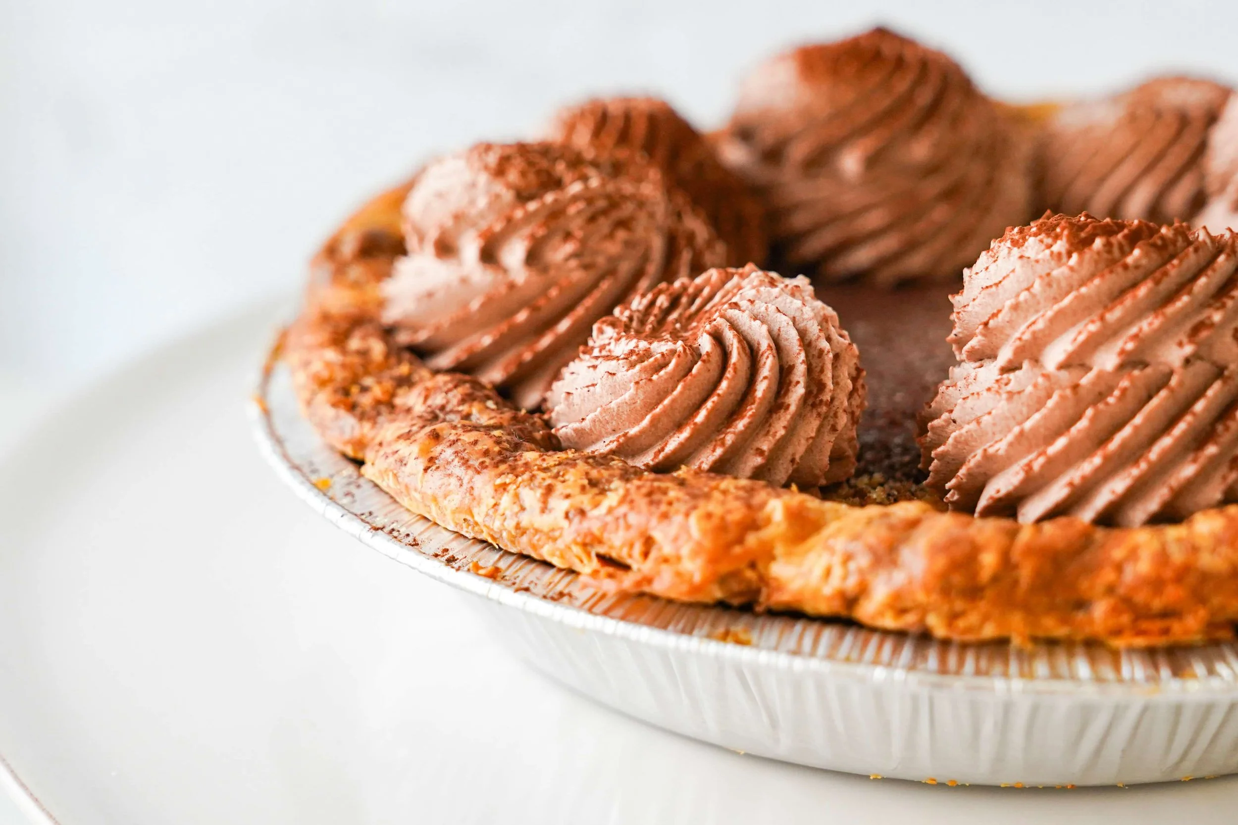 Close-up of chocolate cream pie with whipped topping in metal pan.