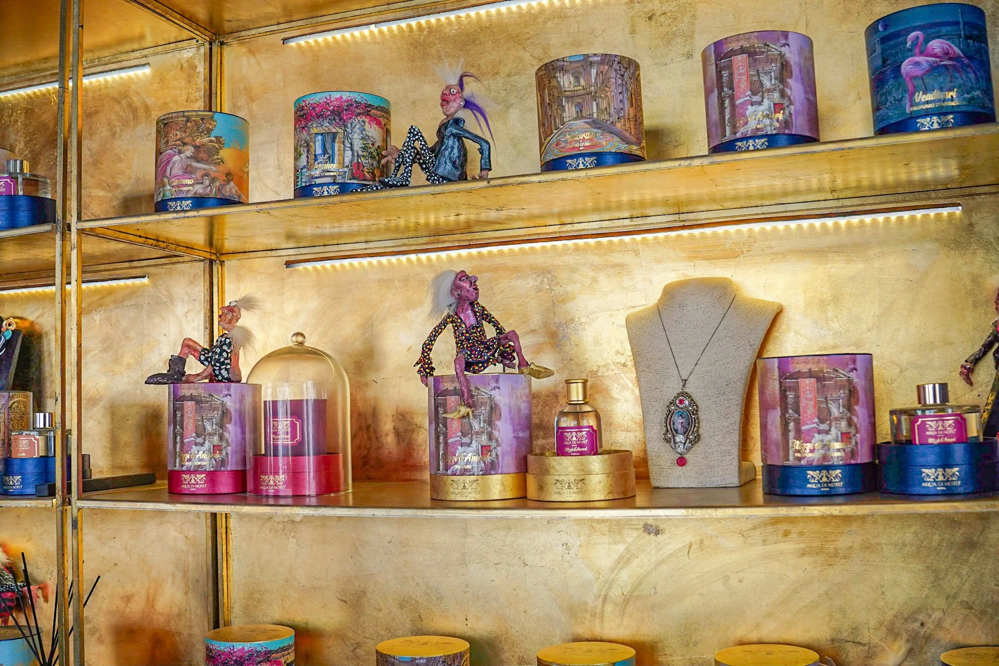 Shelves displaying decorative bottles, figurines, and a necklace on a bust.