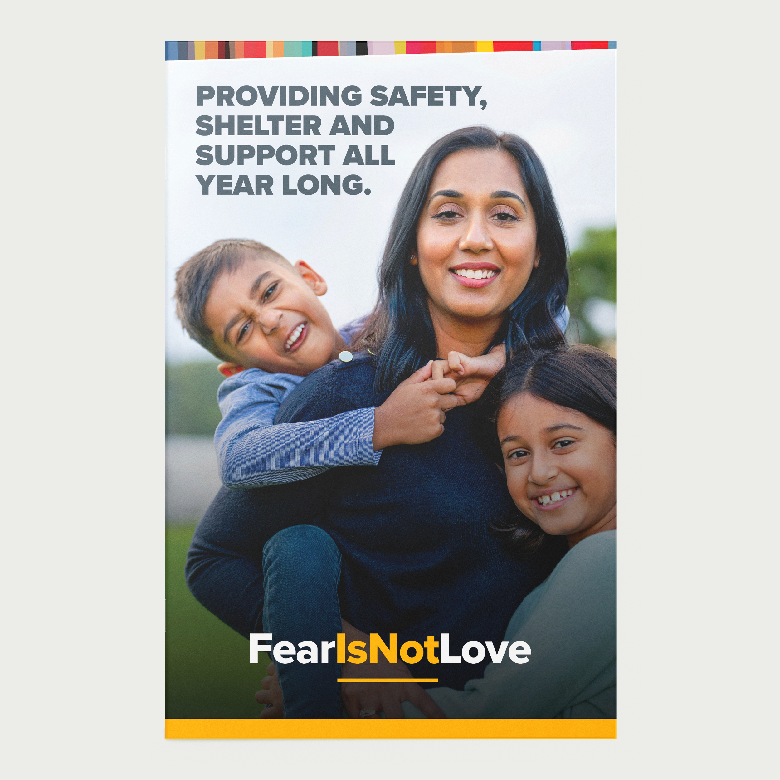Graphic Design:  A smiling mother and 2 children embracing in the park. Text above them reads, 'Providing safety, shelter and support all year long.' The bottom text states 'Fear Is Not Love' with a colorful border.
