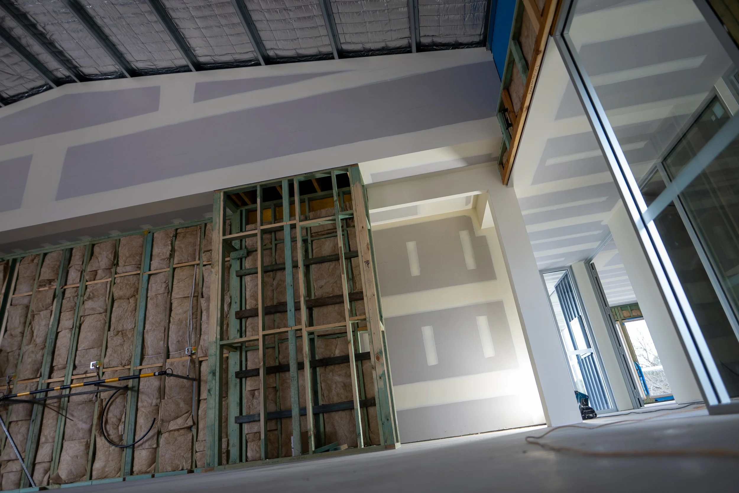 Interior of a building under construction, showing framing, insulation, and partially finished walls and ceilings.