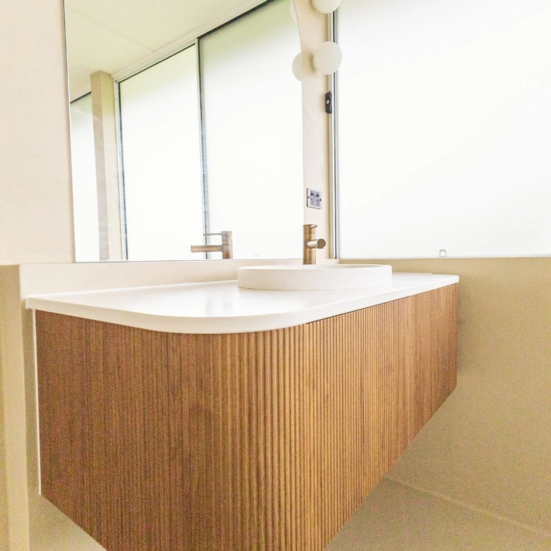 Sleek, sculptural, and smartly designed 🛁✨
This custom bathroom renovation features ribbed curved cabinetry in rich timber tones, a seamless stone bench, and a soft neutral palette that brings warmth and modern elegance to the space. The floating v