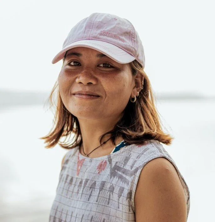 Woman wearing a pink cap and sleeveless top outdoors by water