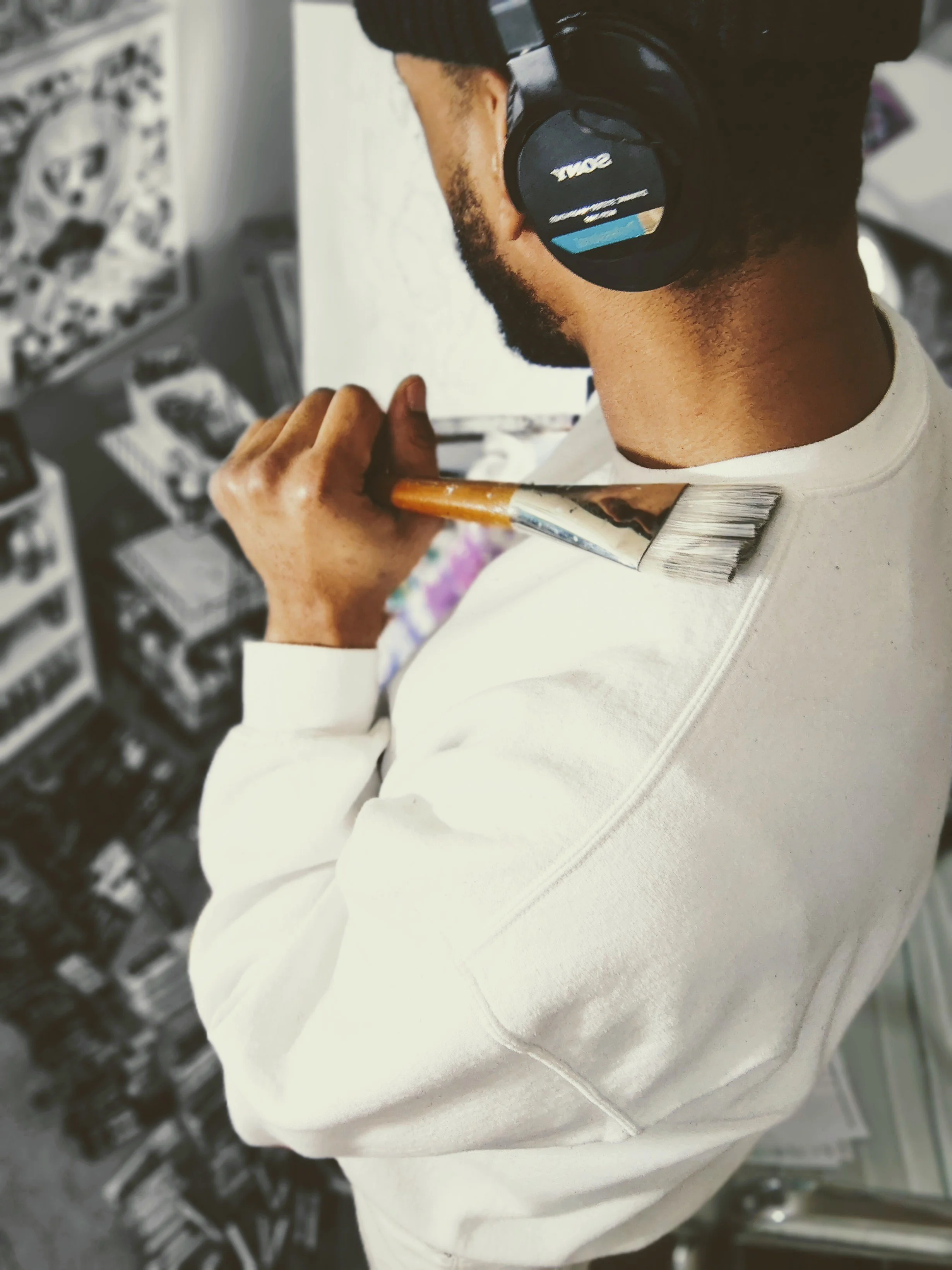 Emerging artist dedicated to his dream. Daydreaming holding a paintbrush in his art studio.
