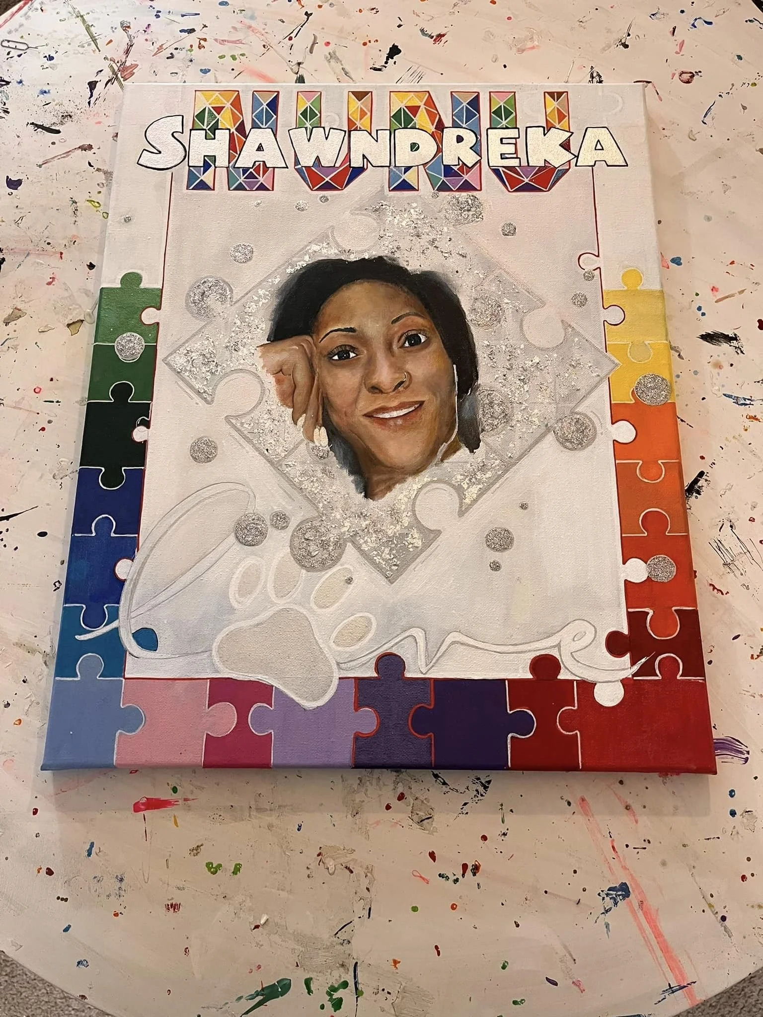 Colorful puzzle-themed artwork with a woman's portrait in the center, bold rainbow letters spelling "Shawndreka" above.