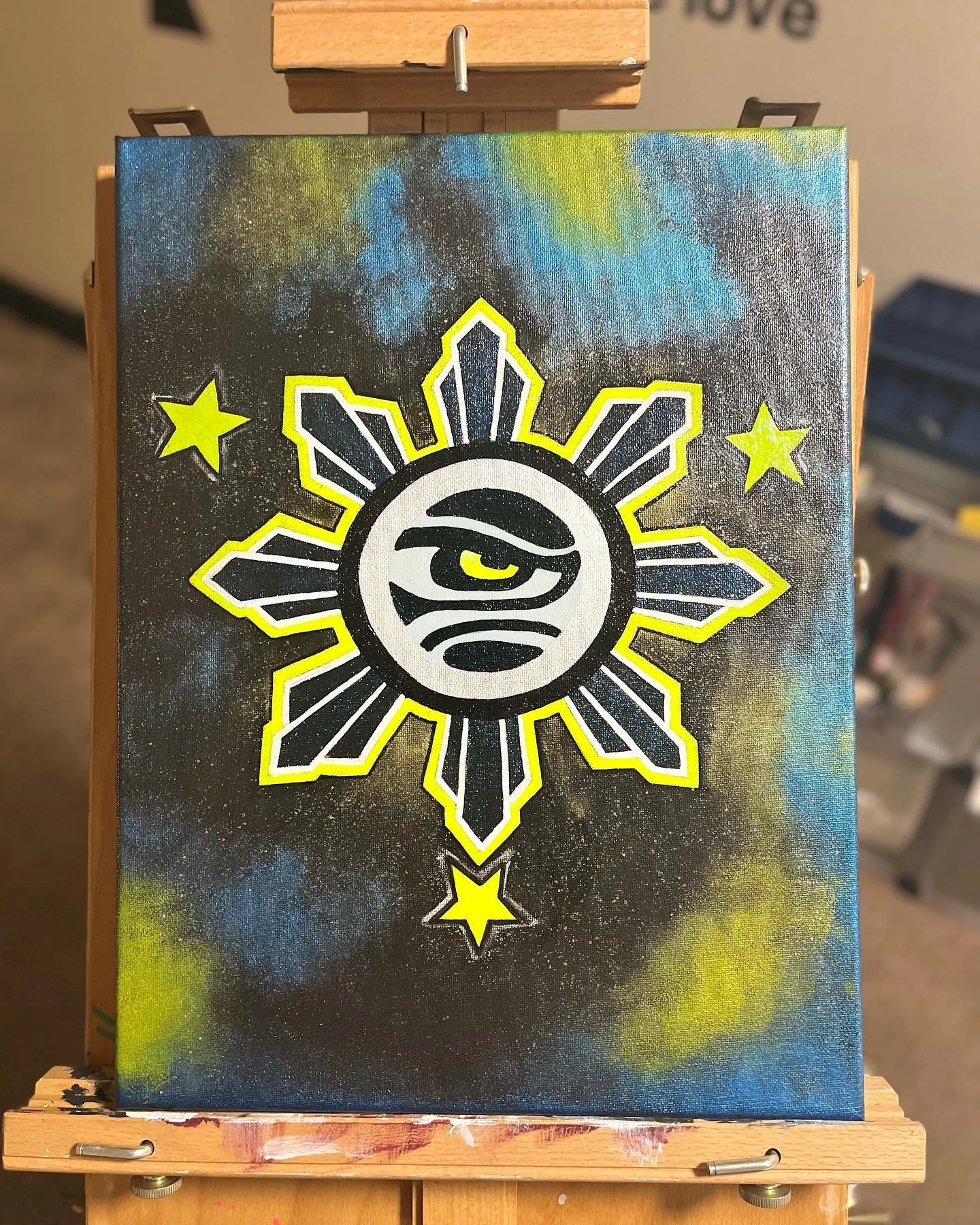Abstract painting of a stylized sun with an eye in the center, surrounded by smaller stars on a dark, cloudy background with blue and yellow hues, hand painted by PleasantArt