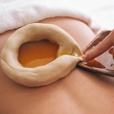 A close-up of a person's belly with a belly button and a finger inserting into a small opening with a yellowish liquid visible.