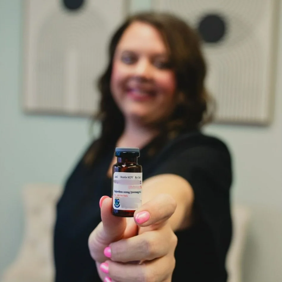 Person holding a small vial with a label, blurred background.