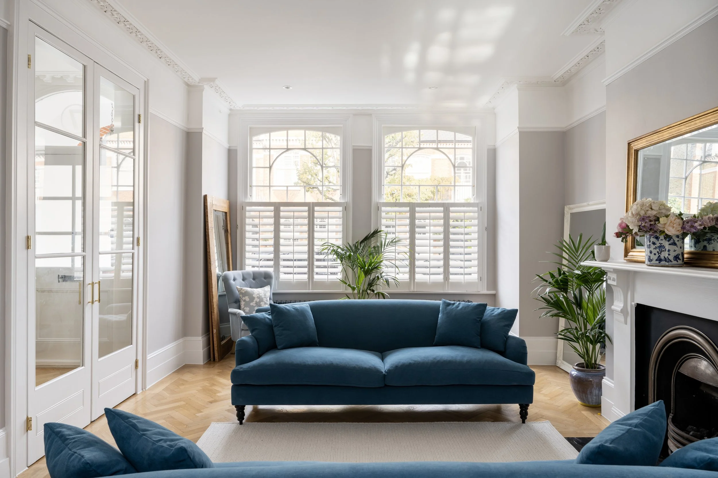 Modern living room with blue sofa, large windows, and natural light