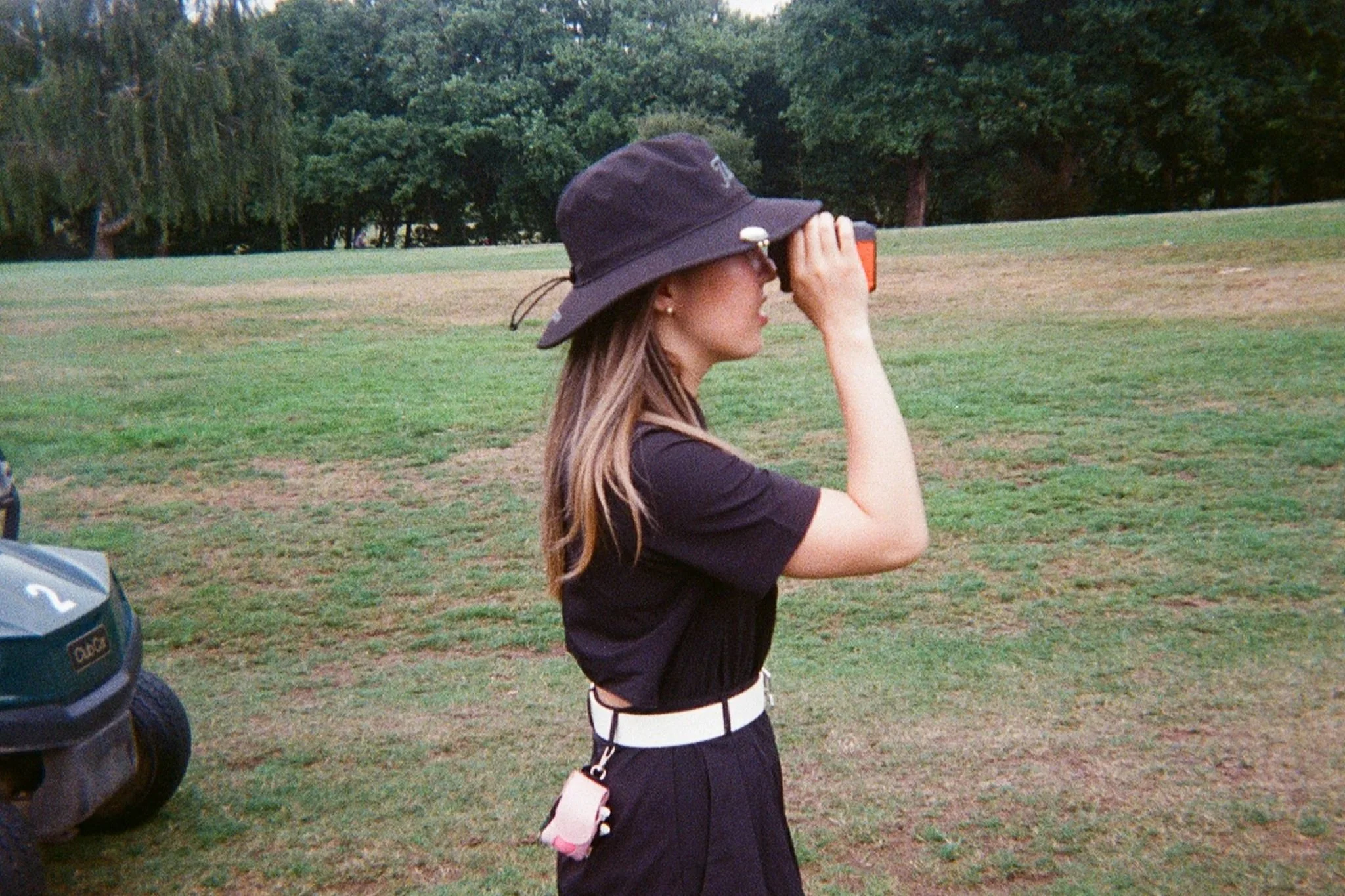 Female golfer using her viewfinder to find out how far she needs to hit the ball.