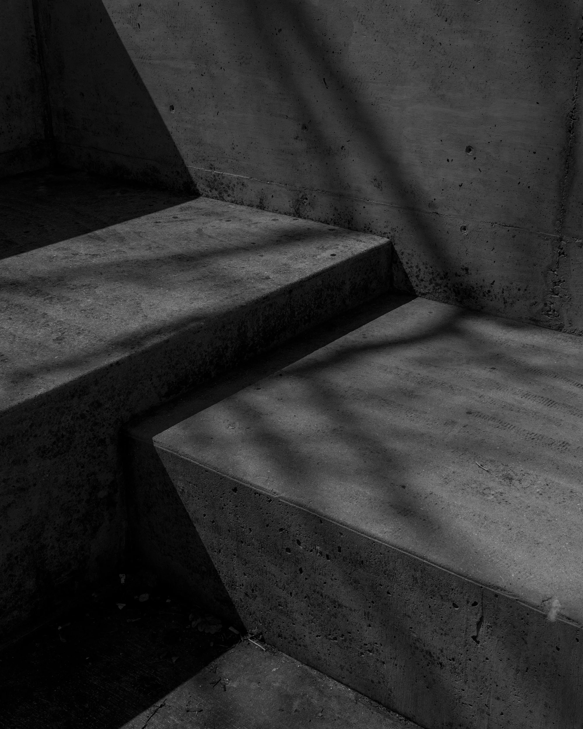 Concrete stairs and wall with shadows cast across the surfaces.