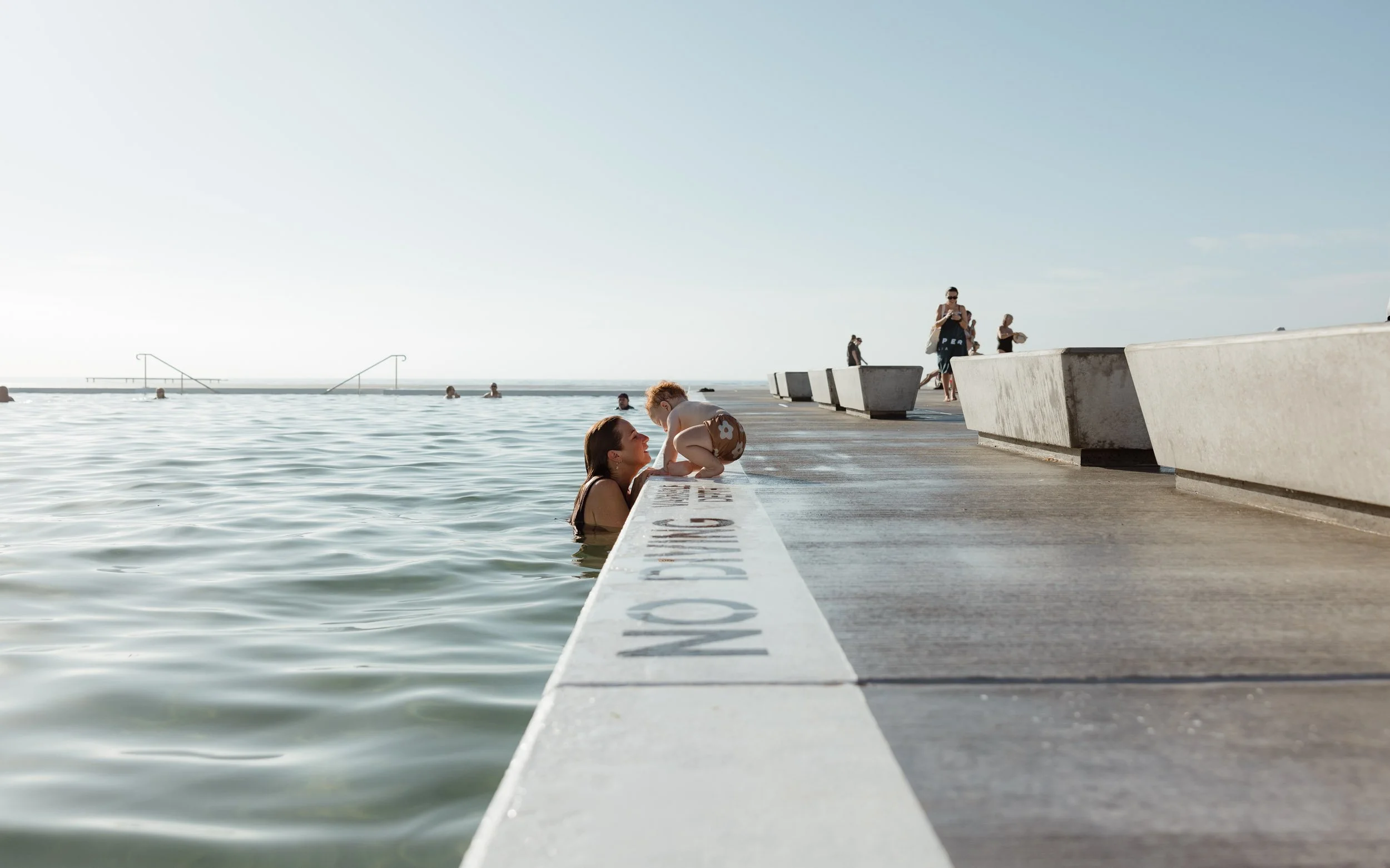 Newcastle documentary family photographer captures mum dad and baby at Newcastle Ocean Baths
