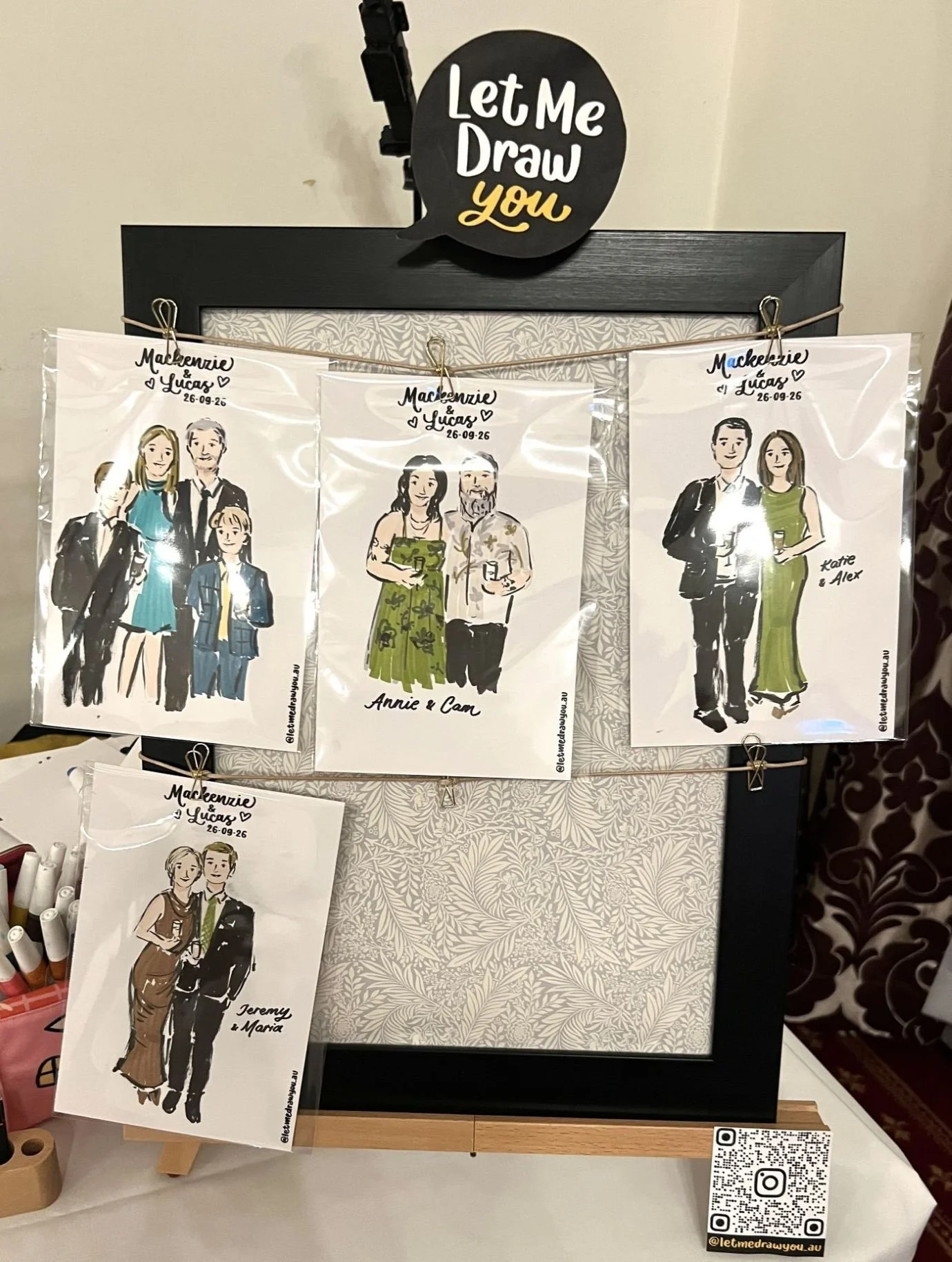 Full-body live guest illustrations by Let Me Draw You displayed on a table