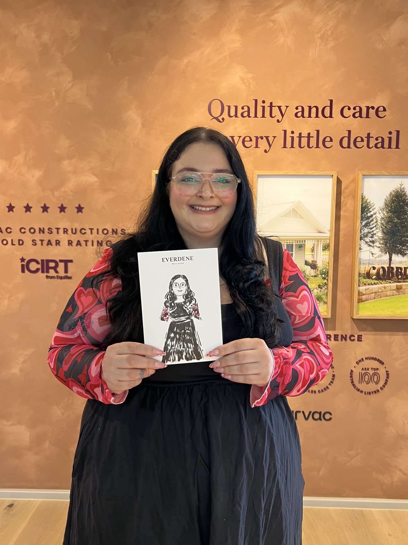 Woman smiling and holding her full body illustration at a brand activation
