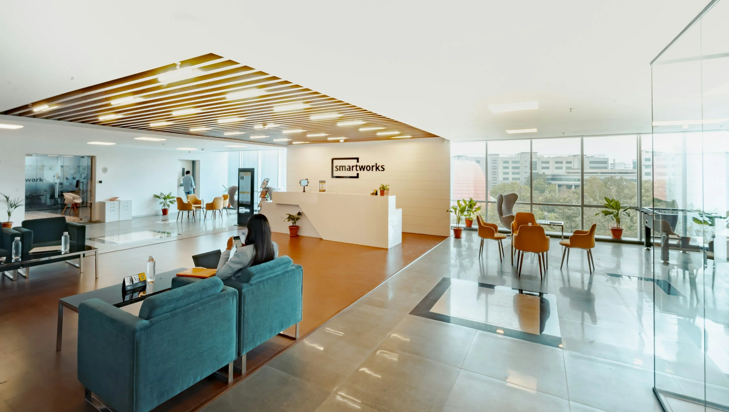 Bright modern coworking space with lounge seating, reception area, and large windows overlooking the city