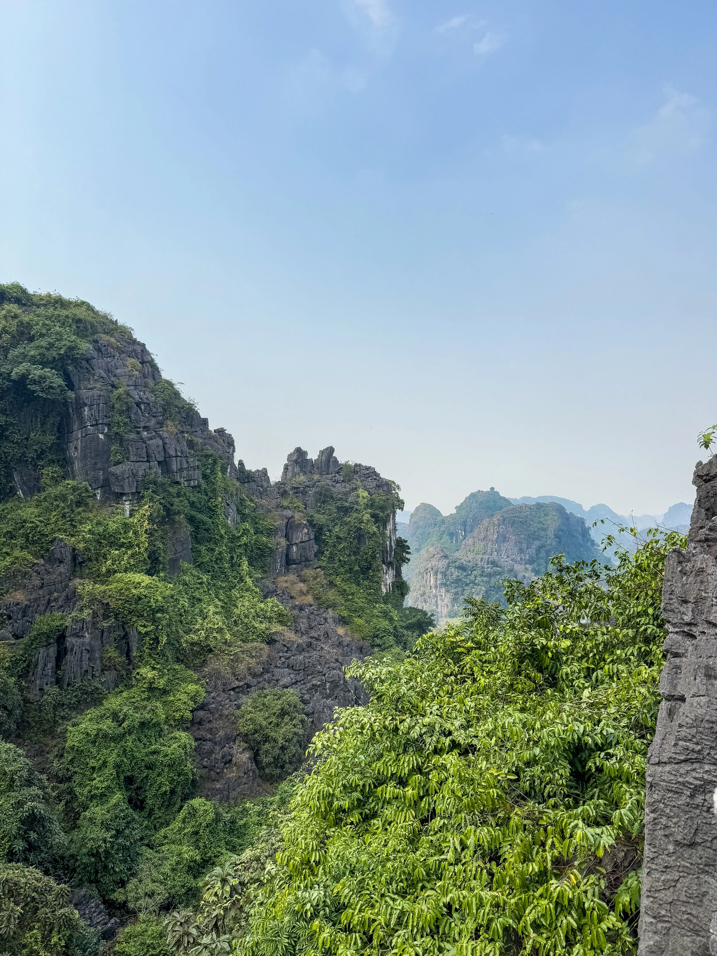 Scenic view of limestone mountains with lush green vegetation under a blue sky.