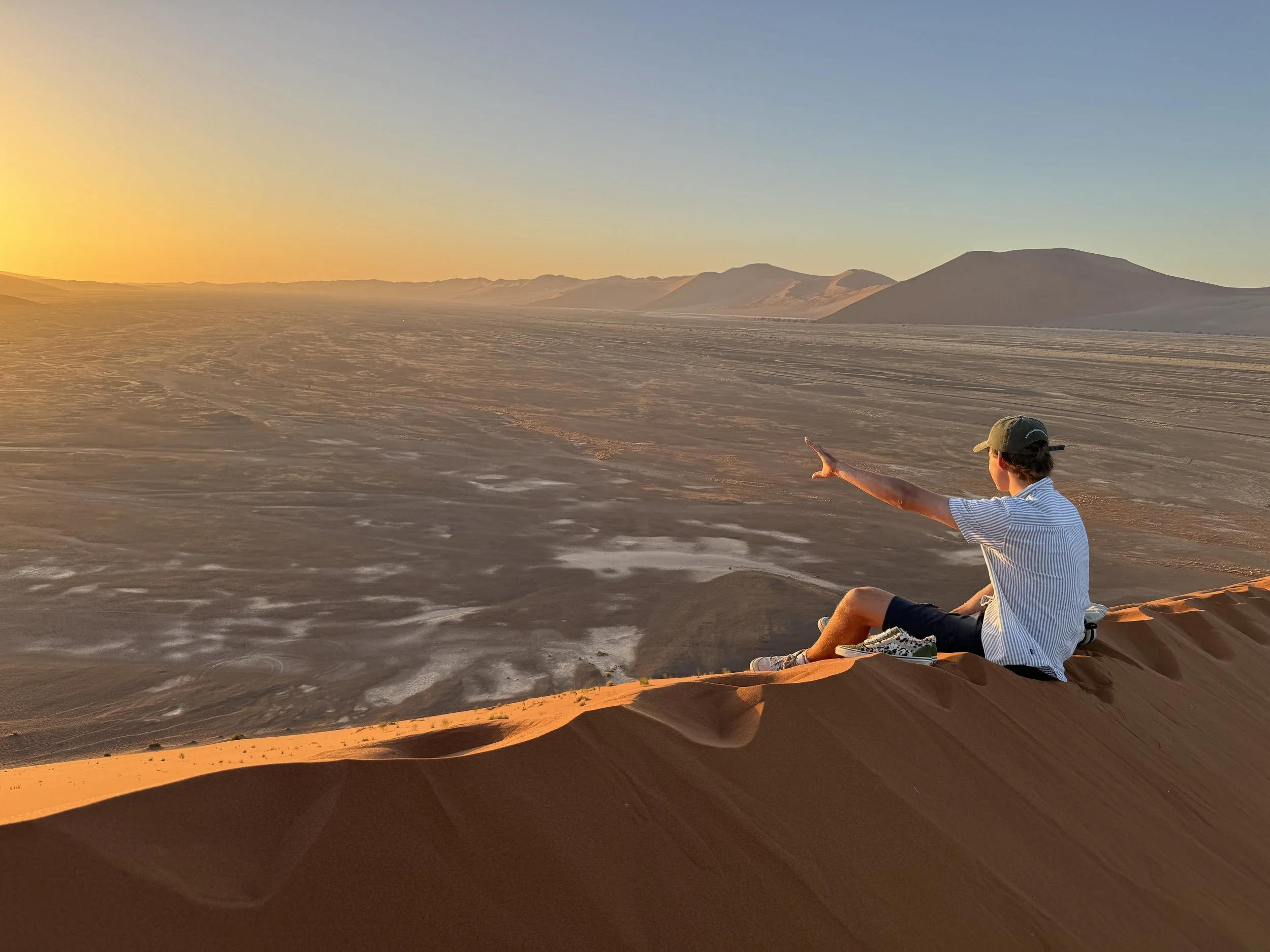 Watching the sunset from the Sossusvlei dunes Namibia, the Namib desert landscape glowing orange
