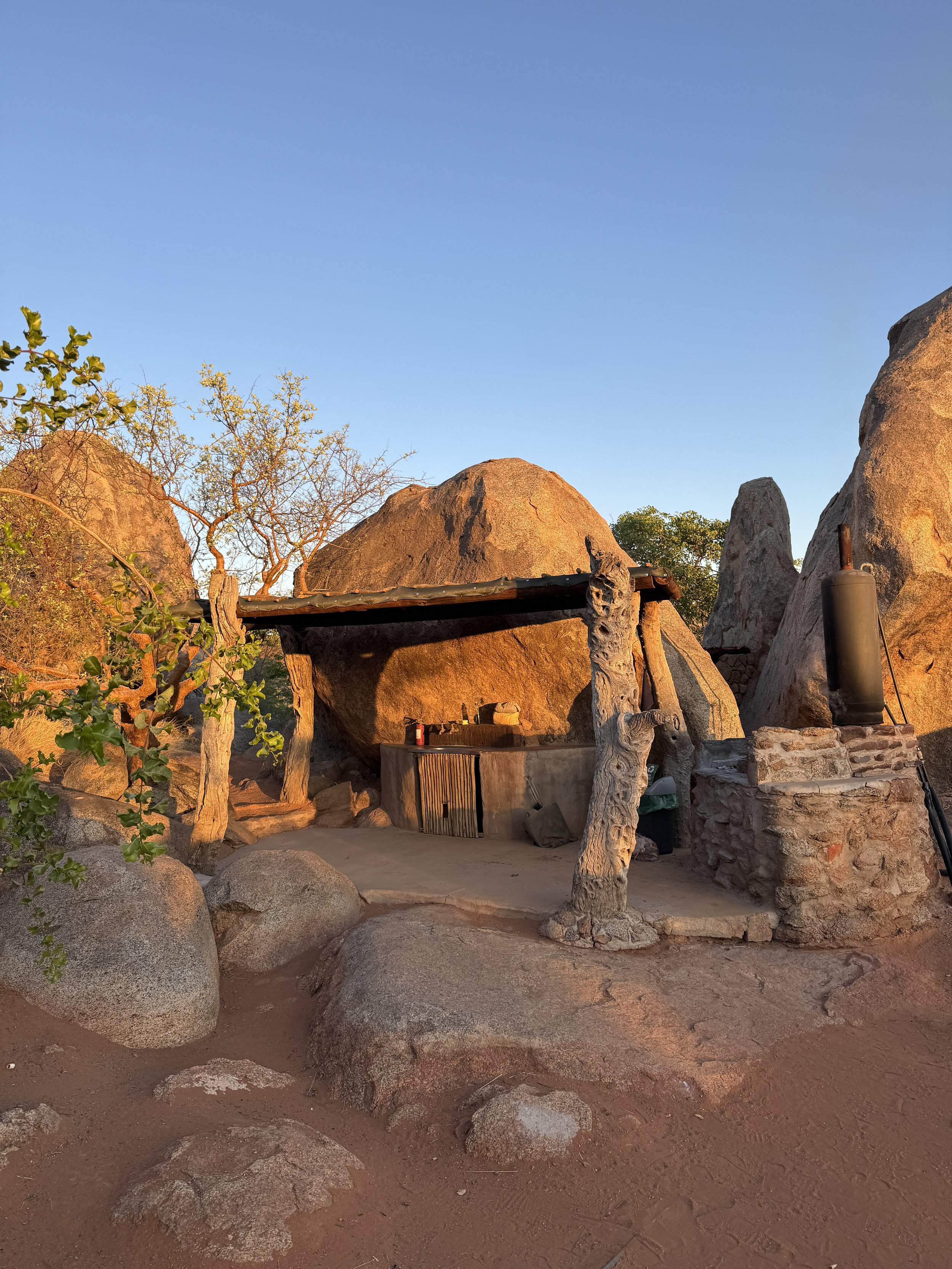 A rustic outdoor kitchen built into a rocky landscape at a campsite in Damaraland Namibia, a remote desert region with dramatic rock formations and valleys