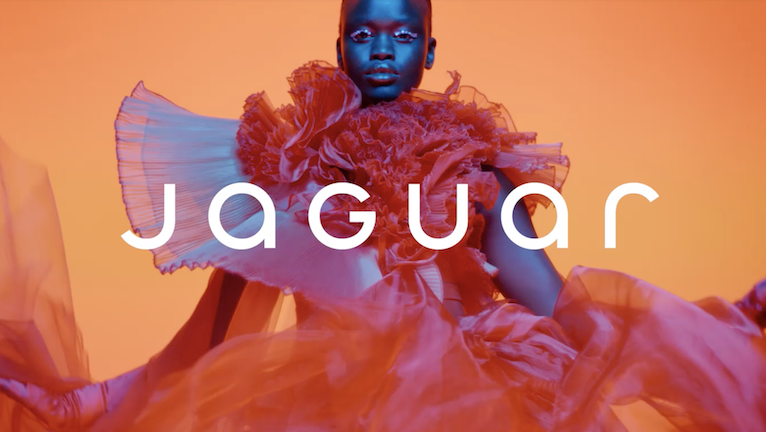 new jaguar wordmark, over a stylized model and orange backdrop