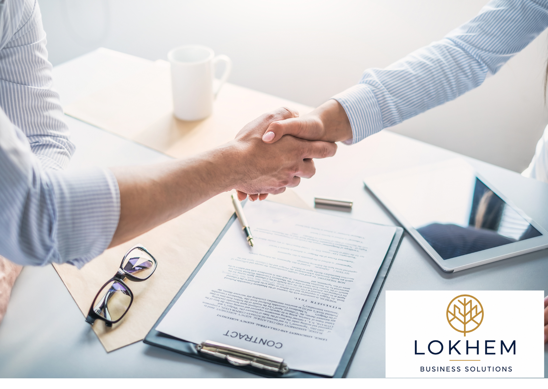 Two businesspeople shaking hands over a desk with a contract, clipboard, glasses, pen, tablet, and a mug on it, with a business logo and name "LOKHEM BUSINESS SOLUTIONS" in the bottom right corner.